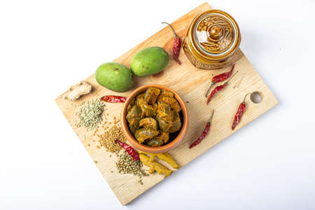 Mango Pickle setup with jar on wooden background with green mango slices