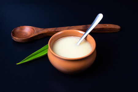 Pure cow ghee in ceramic bowl on black background with ghee spoon in handの写真素材