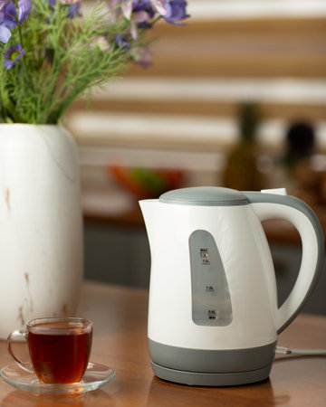 Modern electric kettle, cup on a wooden table in the kitchenの写真素材
