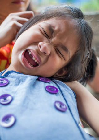 Closeup crying little asian girl with a broken teethの写真素材