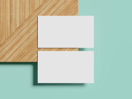 A professional business card mockup resting on a textured wooden surface, highlighted by a soft shadow on a pastel teal background for an elegant look.の写真素材