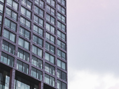 Modern office tower with floor-to-ceiling windows and light sky background.