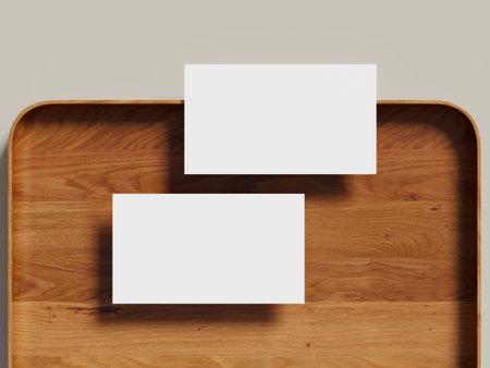 Two blank business cards arranged side by side on a wooden tray with a pastel background.の写真素材