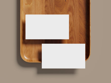 Elegant business card mockup on a light-colored wooden tray with soft lighting.の写真素材