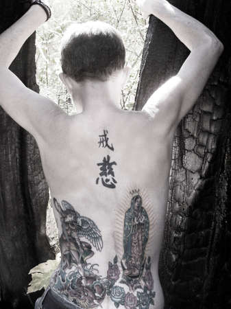 a girl with tattoos in a burned out tree stumpの写真素材