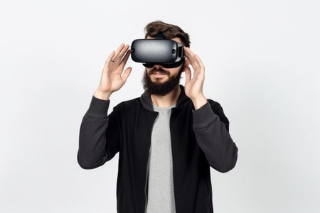 Young man with beard wearing virtual reality goggles on a white background.の素材