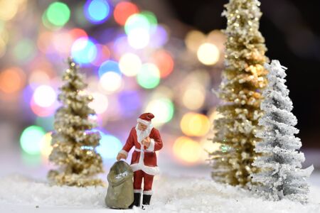 Miniature Santa Claus standing in front of a Christmas treeの写真素材