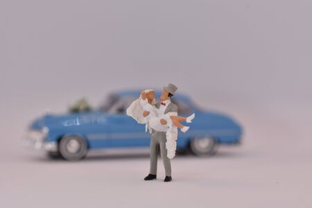 Groom is carrying a bride in front of a wedding carの写真素材