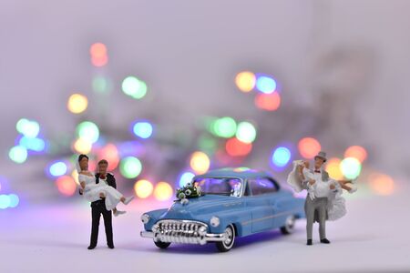 Groom is carrying a bride in front of a wedding carの写真素材