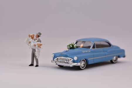Groom is carrying a bride in front of a wedding carの写真素材