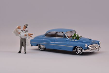 Groom is carrying a bride in front of a wedding carの写真素材