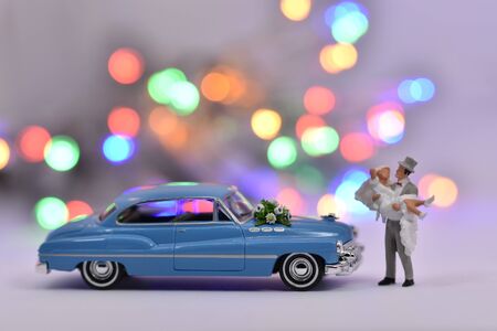 Groom is carrying a bride in front of a wedding carの写真素材