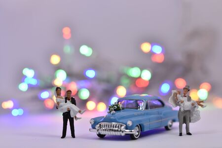 Groom is carrying a bride in front of a wedding carの写真素材