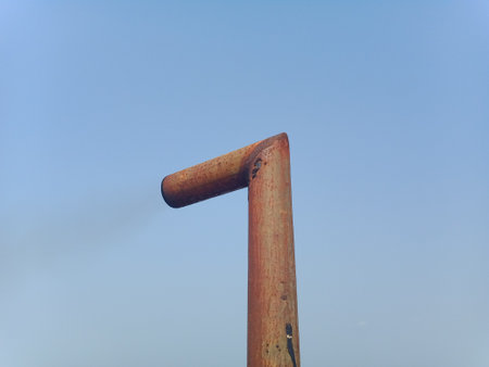 Old rusty iron pole on blue sky background, closeup of photo