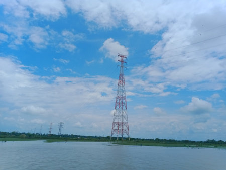 High-voltage tower with blue sky and white clouds background.