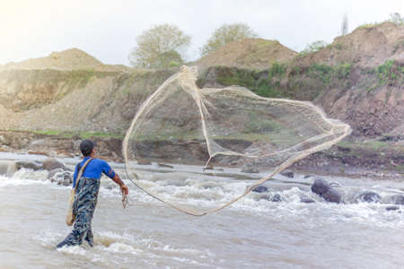Throwing fishing net. Photo shot of water spatter from fisherman while throwing fishing net on the river.の写真素材