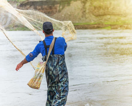 Throwing fishing net. Photo shot of water spatter from fisherman while throwing fishing net on the river.の写真素材
