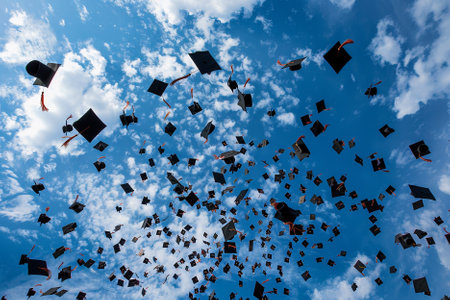 Graduation hats flying in the blue sky with white clouds background.の写真素材