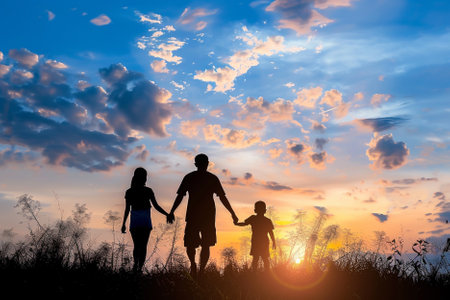 Silhouette of happy family holding hands on sunset sky background.の写真素材