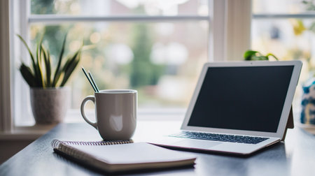 Coffee cup with notebook and laptop on wooden table at homeの写真素材