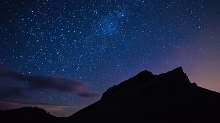 Night sky with stars and milky way over the mountain peak.
