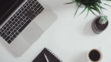 White office desk table with laptop, coffee cup and plant. Top view with copy space, flat lay