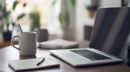 Coffee cup and notebook on wooden table in modern office.の写真素材