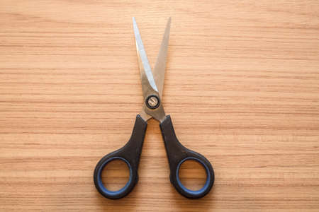 Dirty Black plastic scissor on wooden boardの写真素材
