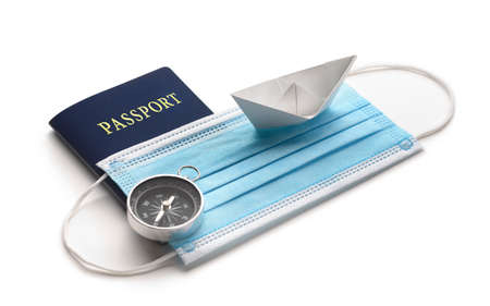Summer holiday during pandemic crisis. Mask with white paper ship and passport on white background.の写真素材