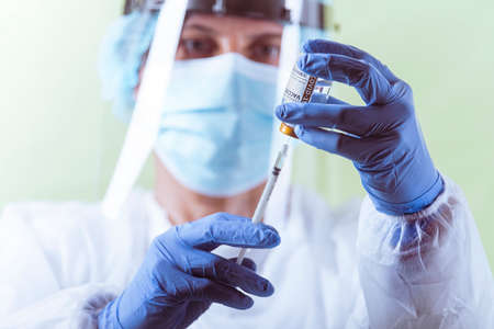 Vaccination, doctor in protective clothes with syringe and ampule