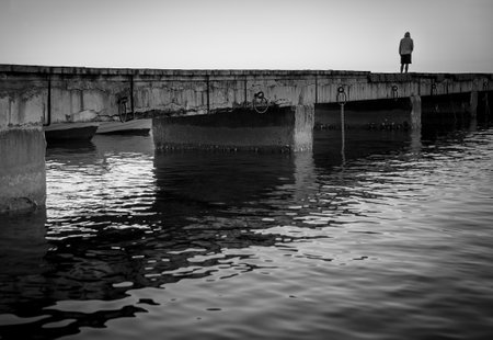 Sorrow. Silhouette of a lonely man on a pier, black and white image.の写真素材
