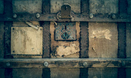 front of an old shabby chest with a padlock and a blank sticker