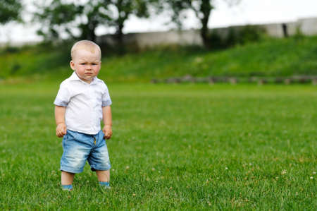 Little boy portrait stands on green grassの写真素材
