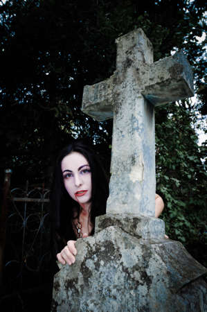 Cross and vimpire girl on cemetery