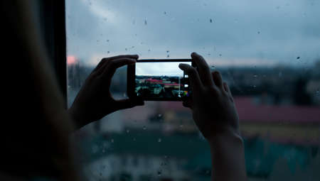 Girl taking photo of evening city with mobileの写真素材