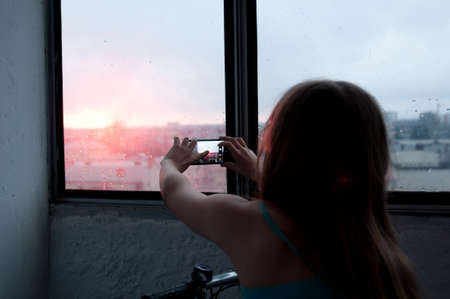 Girl taking photo of evening city with mobile