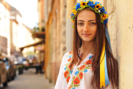 Pretty ukrainian girl stands and looking at camera. She is wearing national clother with poppy flowers and flower crown.の写真素材