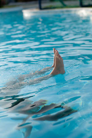 Legs of pretty girl in blue water in poolの写真素材