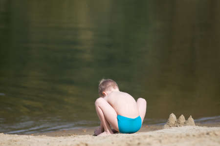 Little boy on the beach playing with sandの写真素材