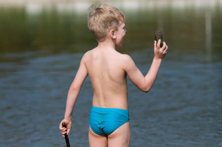 Six years boy rear view standing near the lakeの写真素材