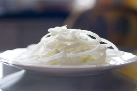 Sliced onion rings on white plate standing on glass transparent tableの写真素材