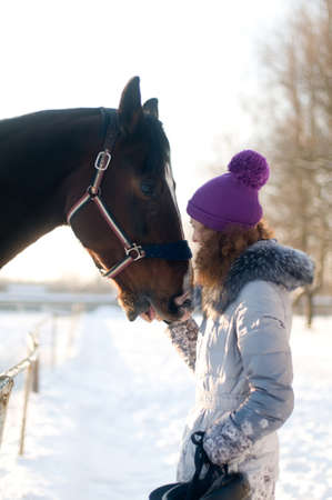 Woman with horse portrait in winter having fun with each otherの写真素材