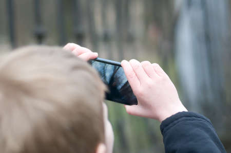 Little boy taking photos on smartphone in parkの写真素材