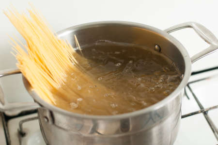 Steel pot on the fire with spaghetti inside boiling in waterの写真素材