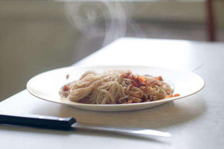 Italian spaghetti with chiken and paprika in white plate on the table with back lightの写真素材