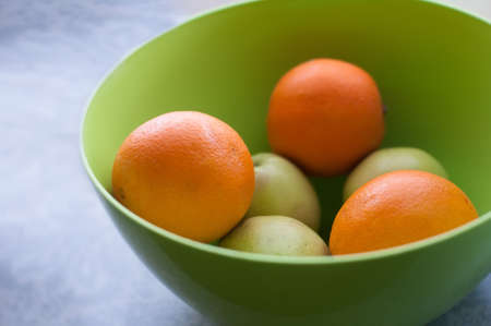 Green apples and oranges in greed bowlの写真素材