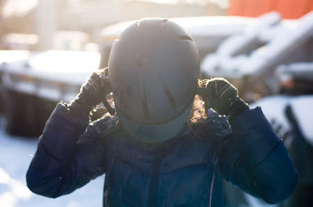 Young girl puts a helmet on her head before riding a horseの写真素材