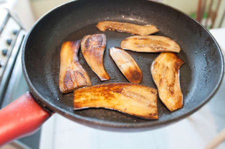 Sliced eggplant on frying pan top view at domestic kitchenの写真素材