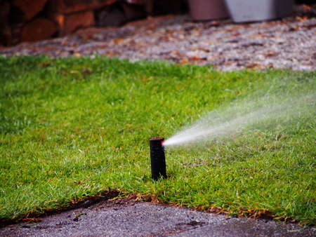 Garden irrigation, sprinkler working. Irrigation system throwing water drops away. Garden irrigation system watering lawn.の写真素材