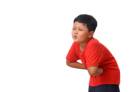 Asian boy in red shirt standing and fells stomach ache. Isolated on white background with copyspaceの写真素材